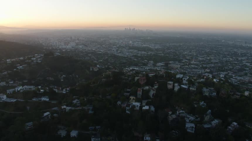 Aerial view of the city neighborhoods over the hills at sunset