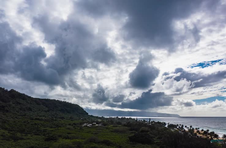 A coastal landscape with a beach with sand with the ocean sky and clouds in the background