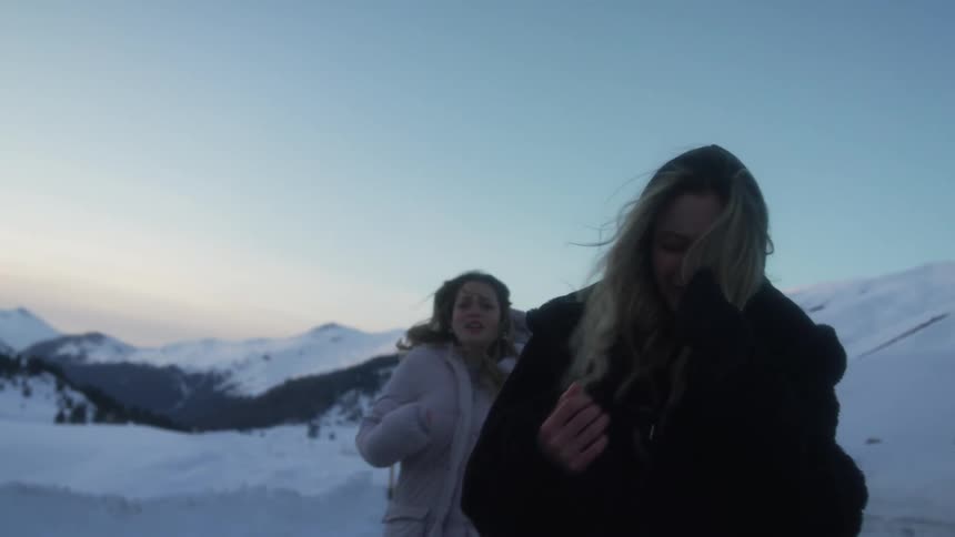 Two women walking up a hill in the winter