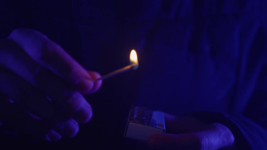 A person lights a match at night