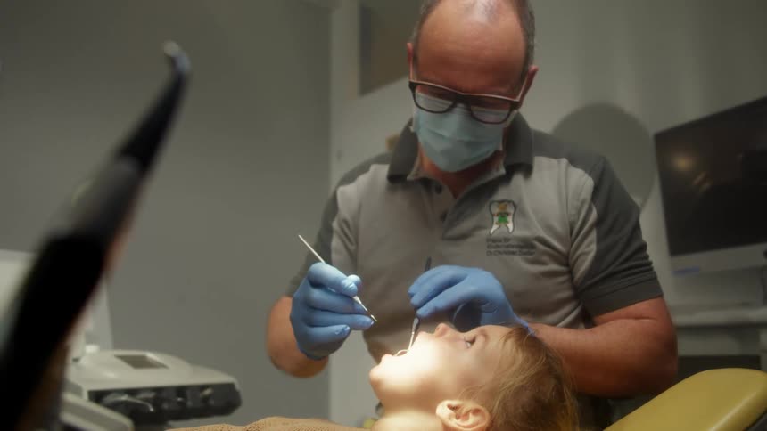 A dentist examines the teeth of a young girl in a dental clinic