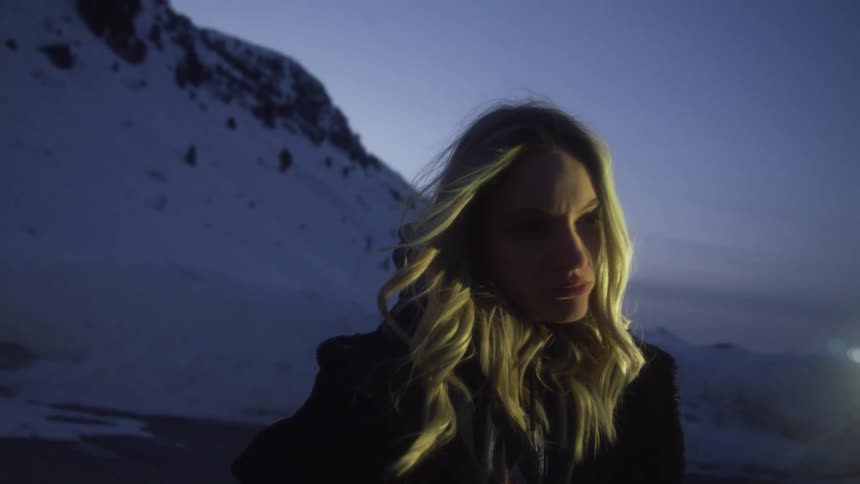 A woman is standing outside at sunset on a windy day