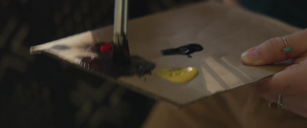 Painter mixes paint on piece of cardboard