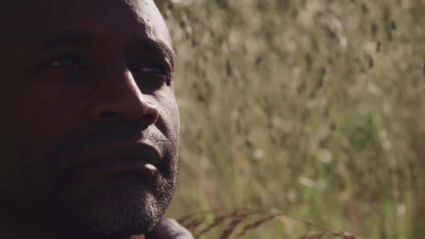 A man sitting outside near grass and vegetation