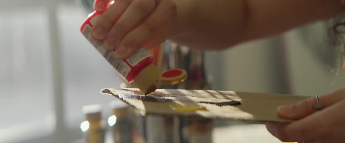 A female puts paint on a piece of cardboard