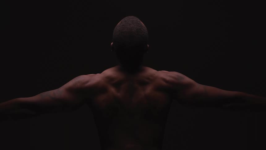 A man in a room stretching with a wall in the background