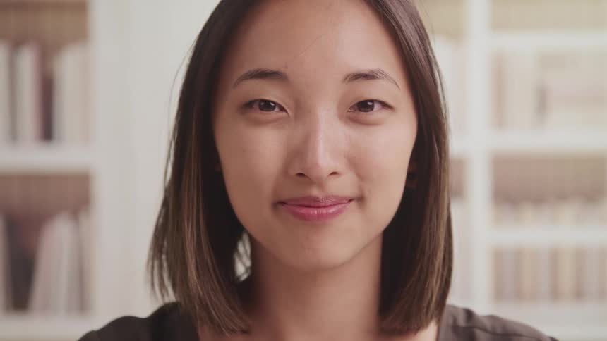 Woman with straight hair looks at the camera smilingly in the library