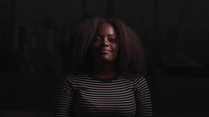 A woman in a striped shirt looking up and smiling in darkness
