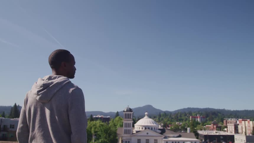 Man wearing gray hoodie looking over a small town