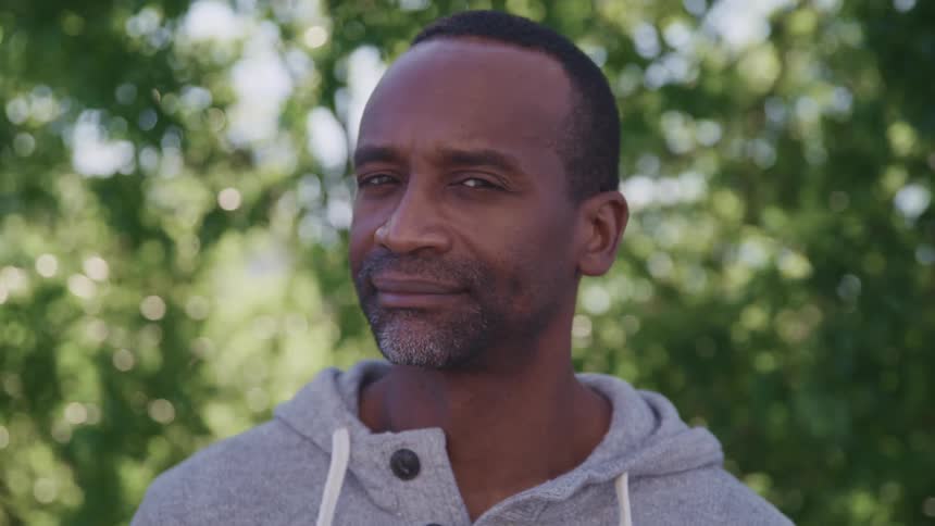 Man standing in the forest turns around to look at the camera
