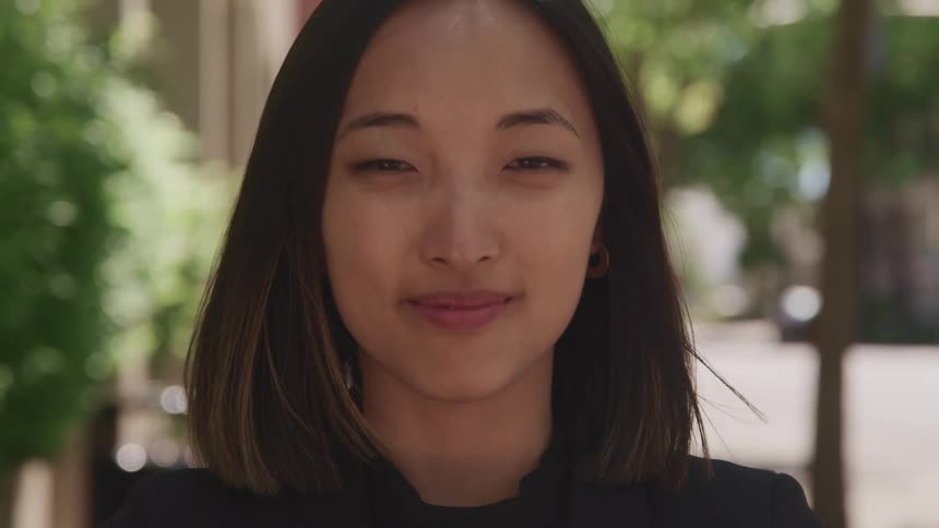 A woman standing outside at daytime smiling for the camera