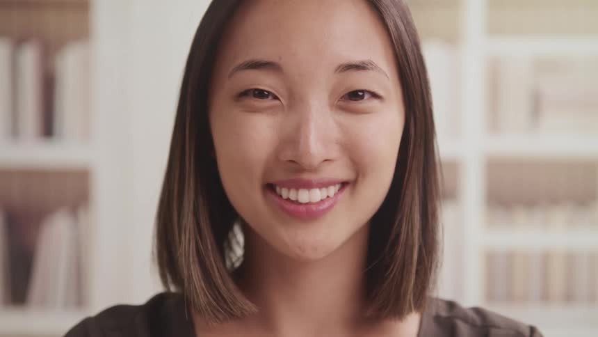Woman faces the camera with eye contact and smiles brightly