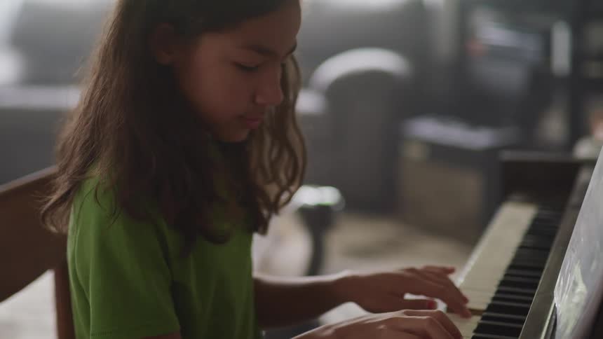 Young girl playing piano in a room at home