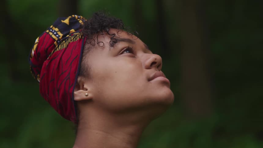 A teenage girl outside looks up towards the sky