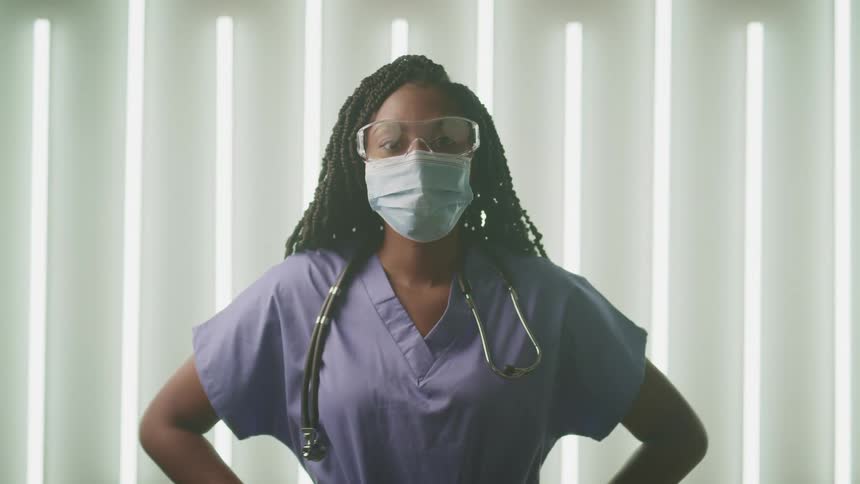 Female doctor wearing surgical face mask looks up at the camera