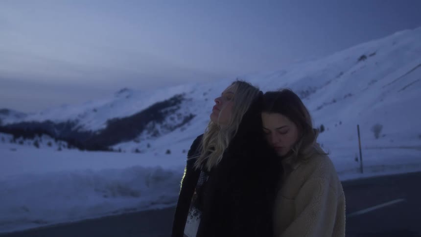 Two women hugging outside in a mountain area