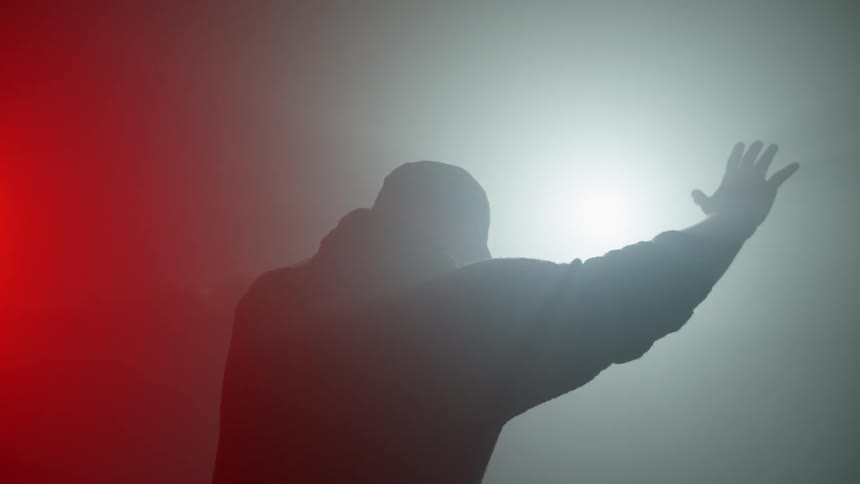 A man leaning towards lights with his hands up