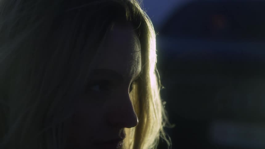 Close up of a blonde young woman standing outdoors at night