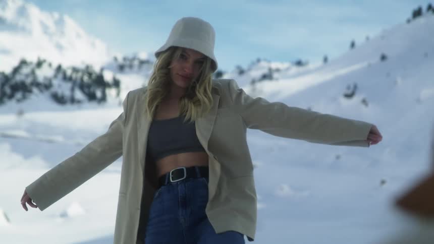 Woman takes pictures of a model with a smartphone on the snow in the mountains
