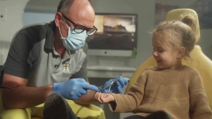 Dentist playing with a little girl sitting in the chair