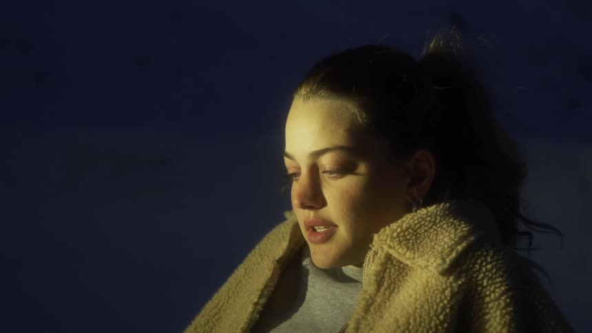 A teenage girl sits on the beach at night