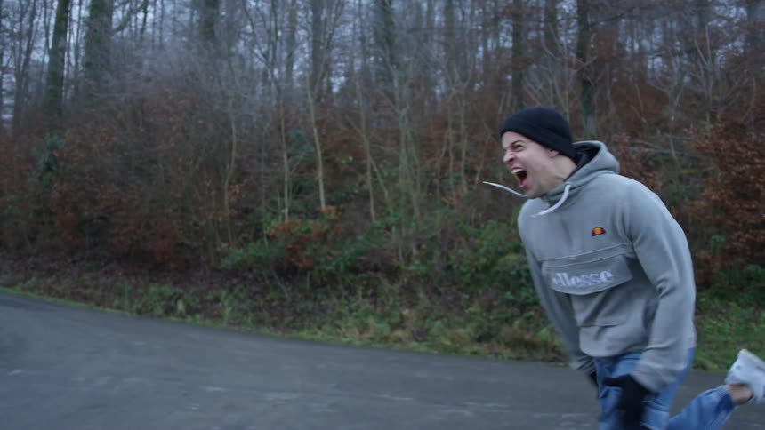 Screaming young man running on a street near the forest