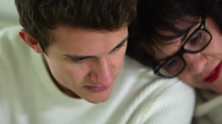 Mother reclined over his son shoulder at home