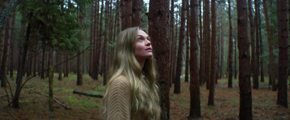 Young blonde woman walking on the forest at daytime