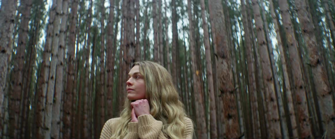 Young woman wearing a sweater walking in the forest