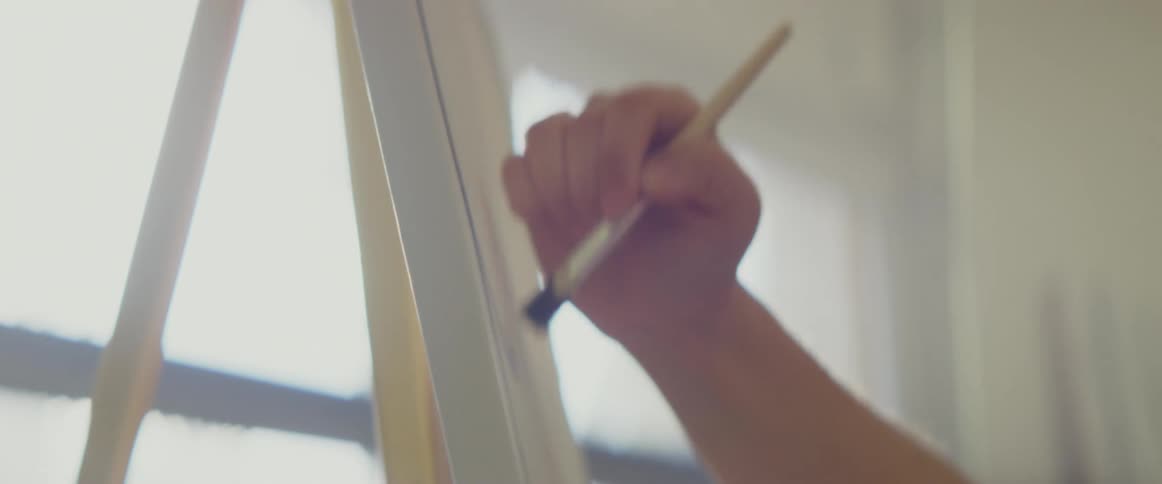 An artist painting on a white canvas in an art studio