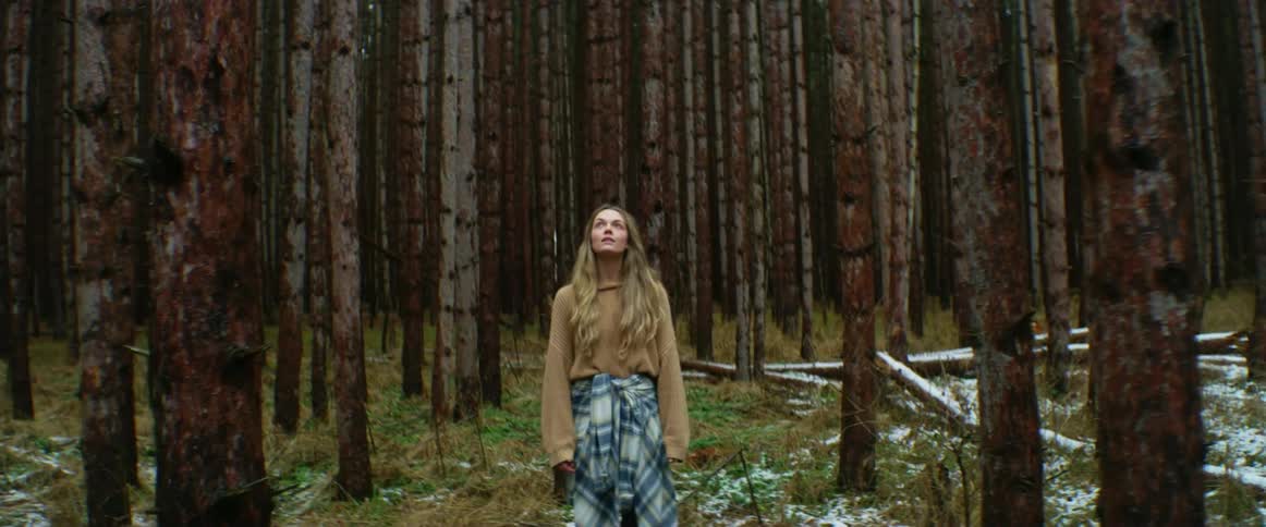Young woman standing in a forest at daytime