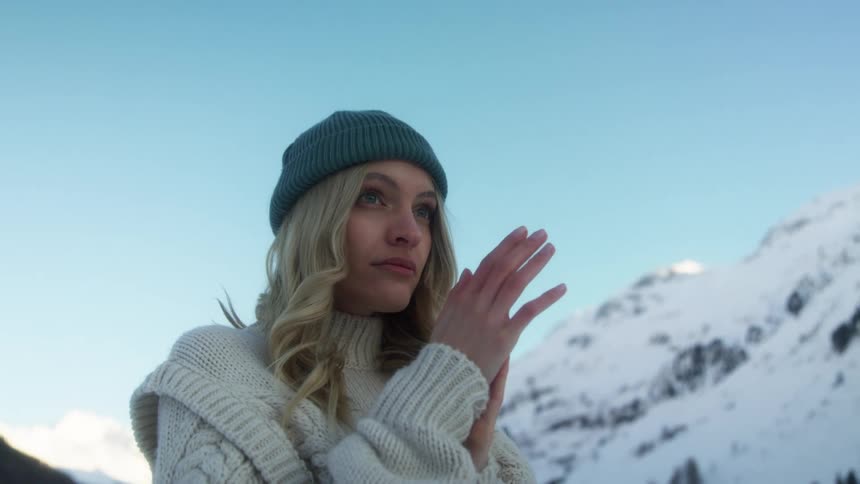 A woman rubs her hands together outside to warm up