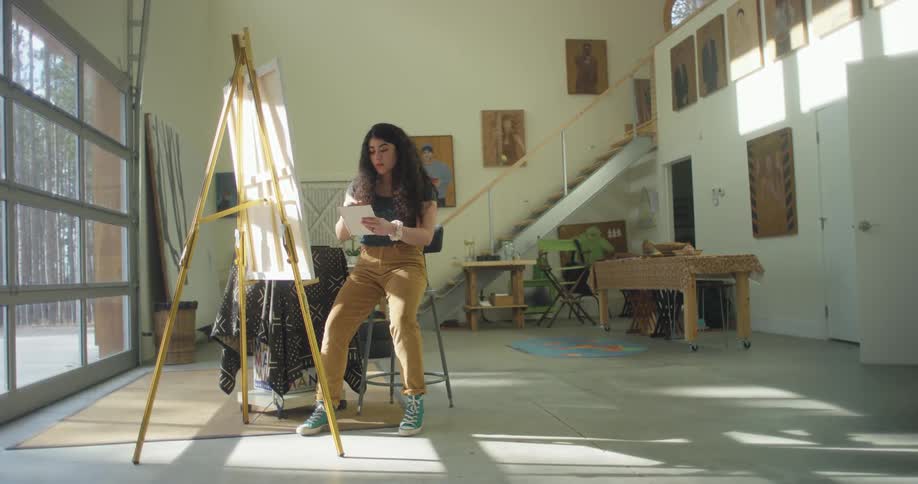 Woman painting with oil over canvas on an easel in a studio