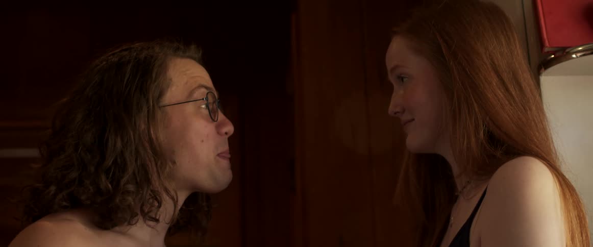 Two friends closely talking to each other in a room at home