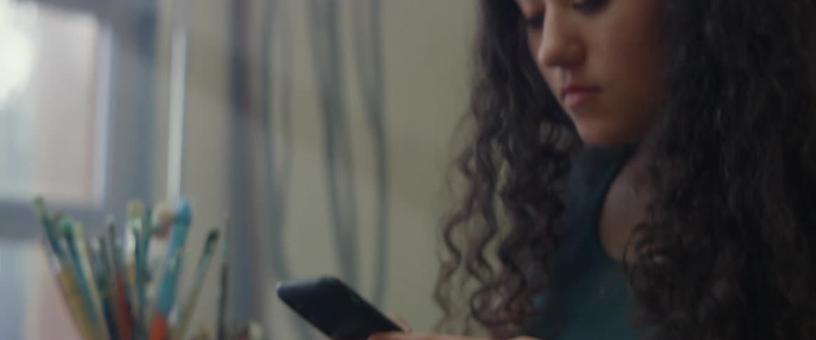 Woman with long curly hair using a smartphone in a room