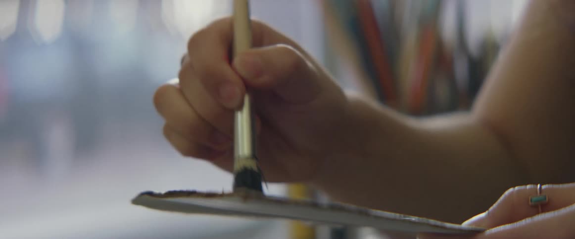 Young woman uses a brush to paint with oil in a studio