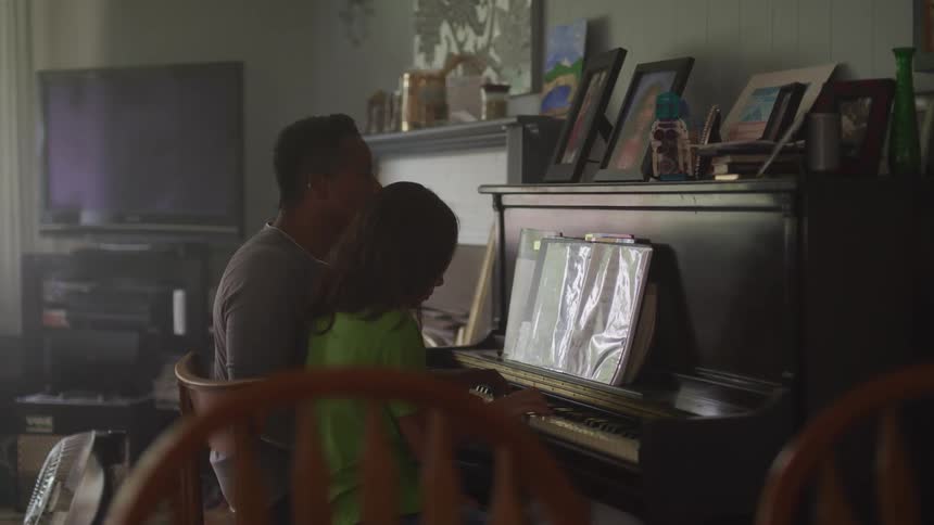 A man sits next to a young girl in front of a piano