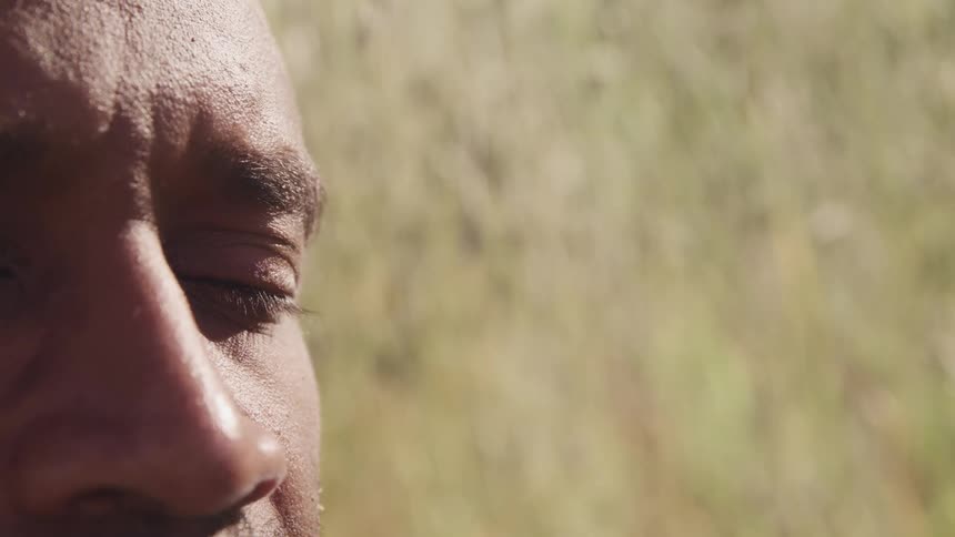 Close up of a mans face sitting in the grass of a field at daytime