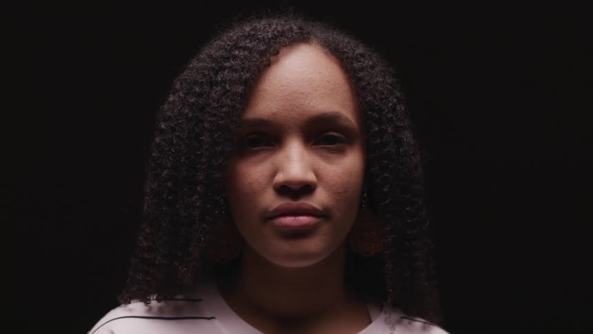 A woman looking up and blinking in front of a black background