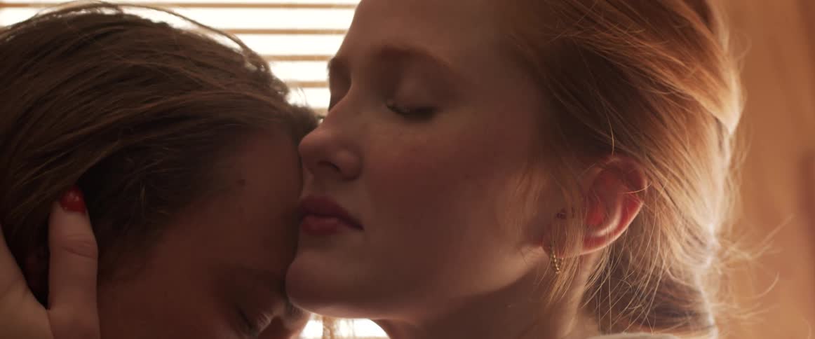 Woman holding her boyfriend head close to her lips inside a room