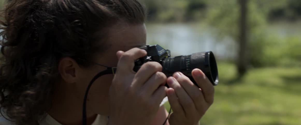 A woman uses a camera to take photographs outdoors during the day