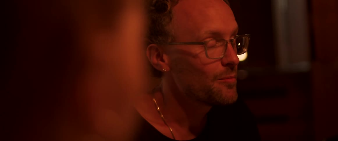 A man is talking with friends in the dark room