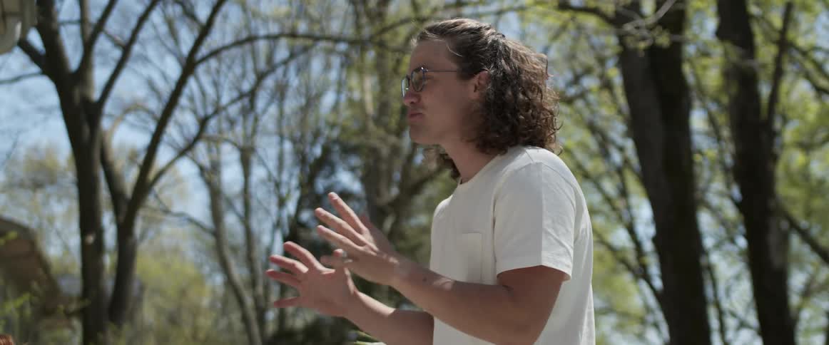 Long haired young man talking in the backyard at home