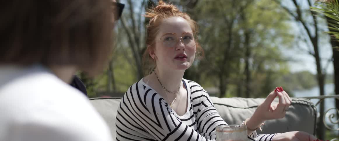 A woman talks quickly with her friends as they sit on patio furniture outdoors