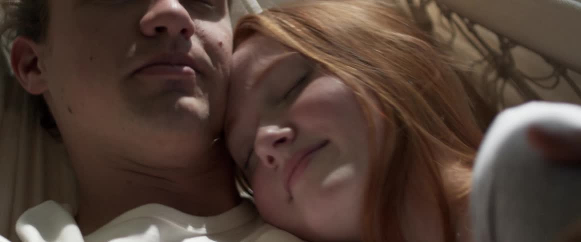 A man and a woman laying on a hammock and hugging