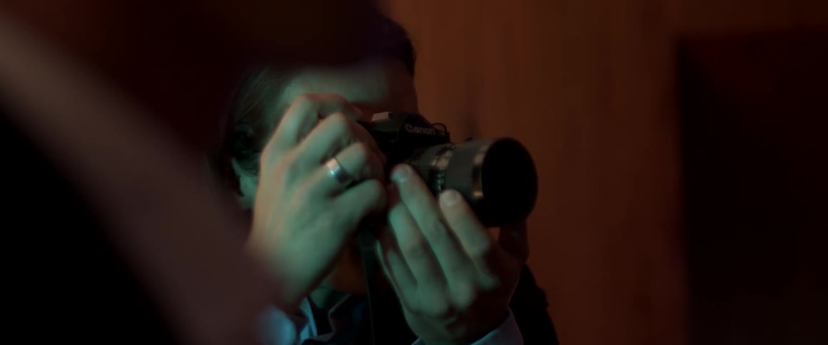 A person taking pictures with a camera inside a room under colorful lights