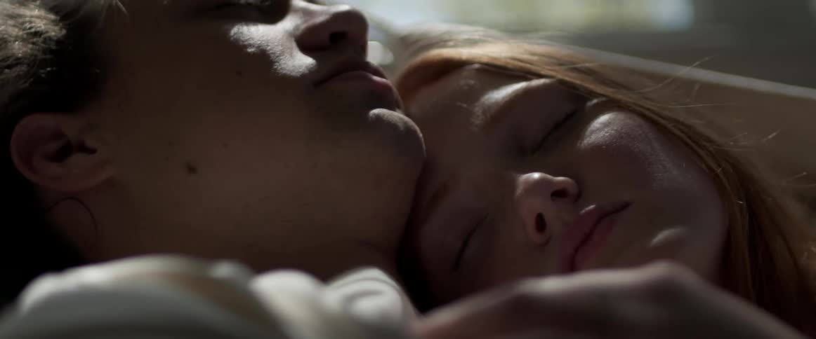 Young couple sleeping on a hammock inside a dimly lit room