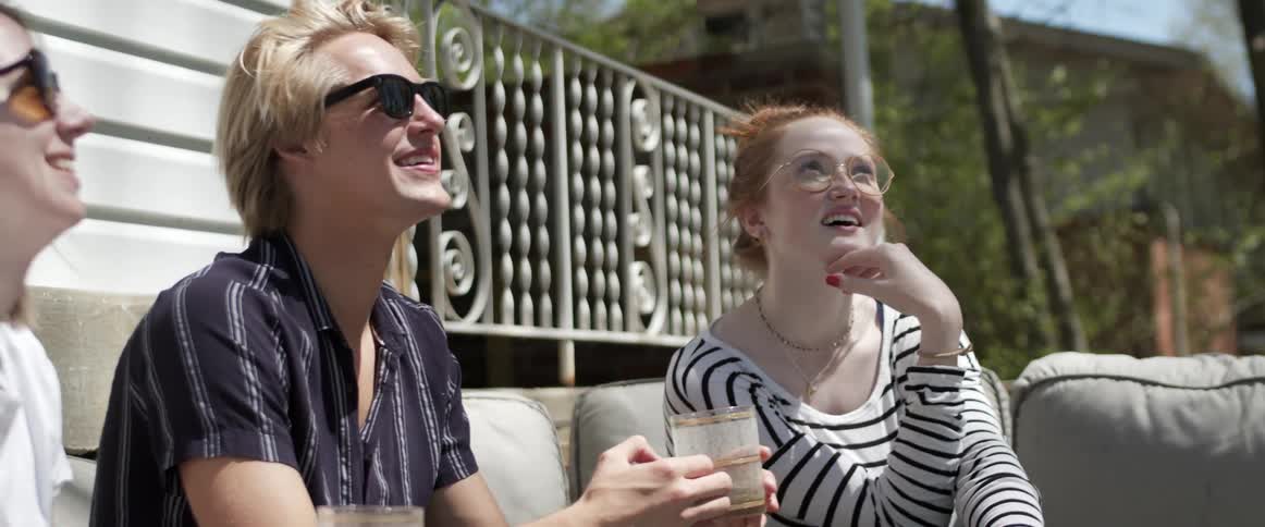 Friends chatting while sitting on an outdoor sofa on a summer day