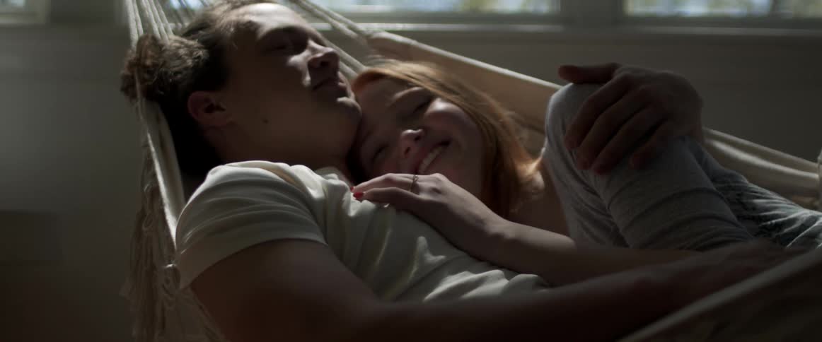 A man and woman cuddling while relaxing in a hammock