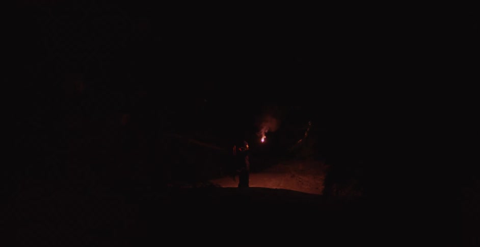 A person raises a torch in the pitch black night